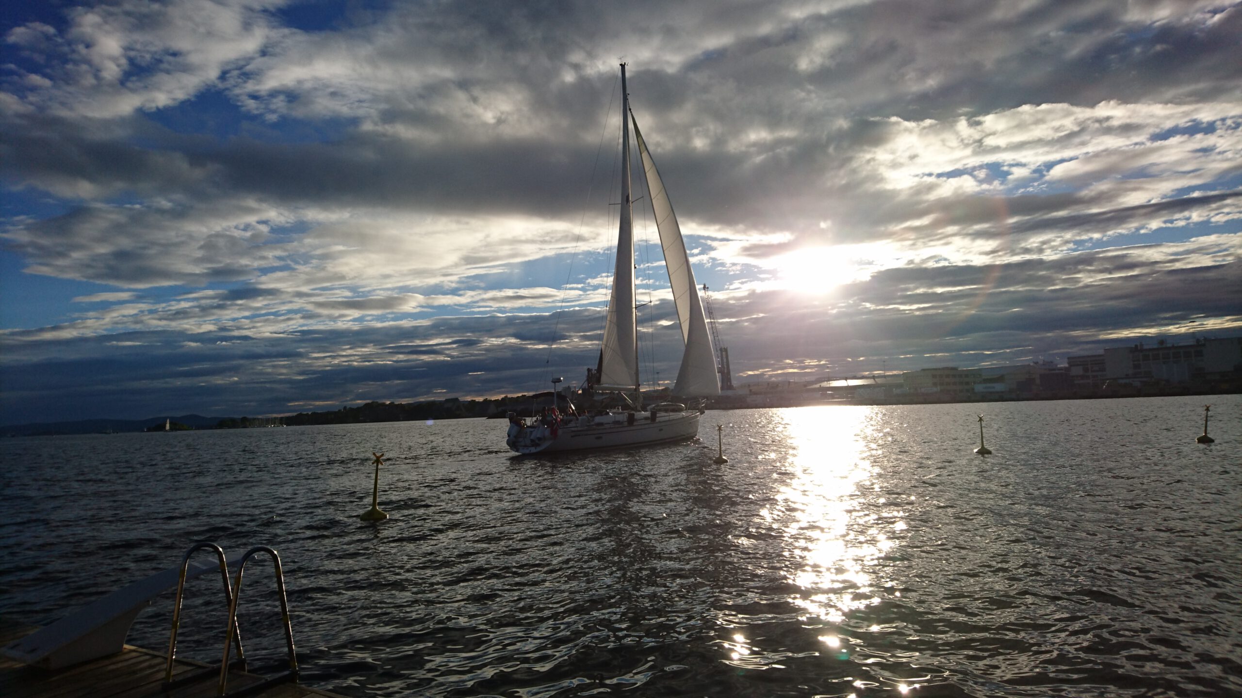 a sailing boat sailing into the sunset in the oslo fjord