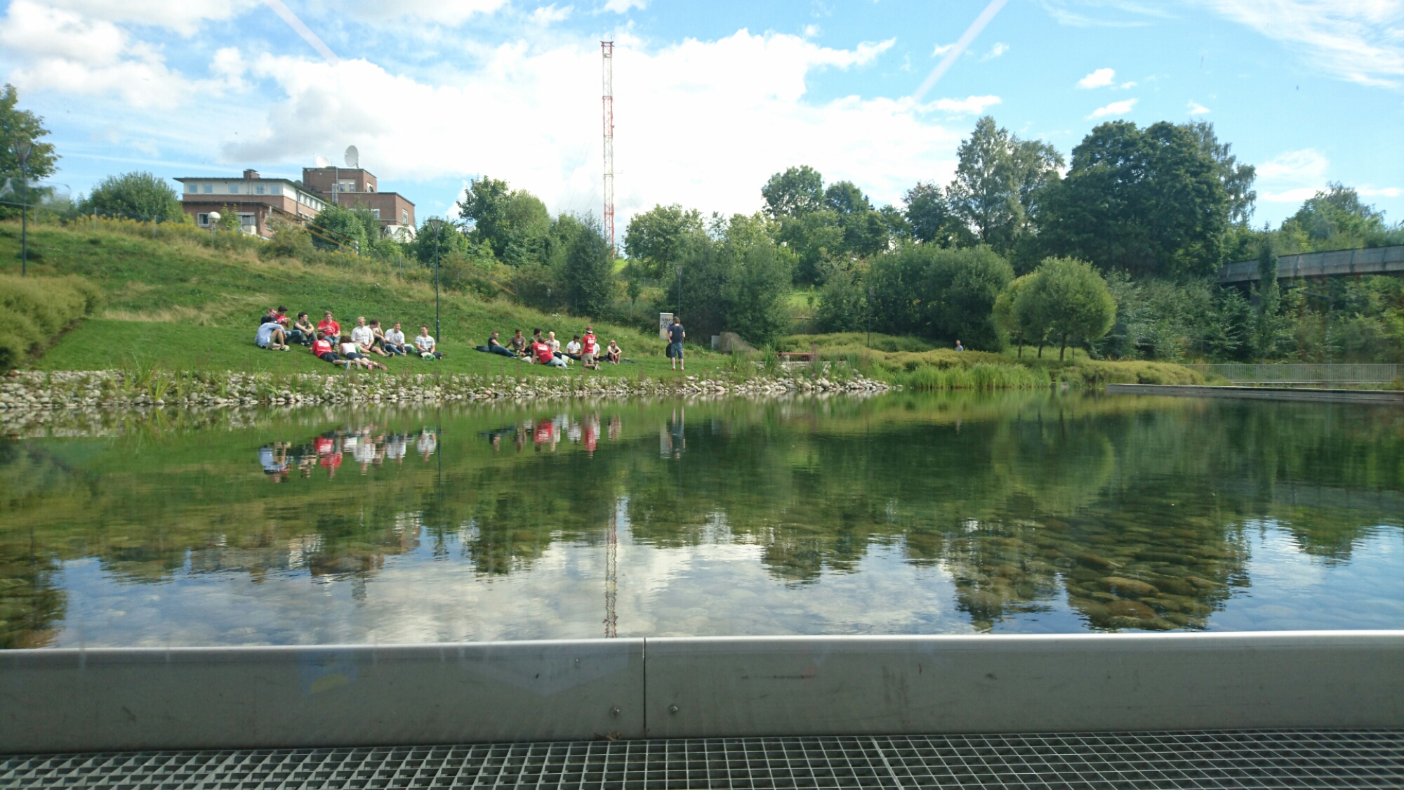 A clear lake with some students sitting around it